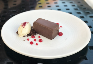 Chocolate torte filled with salted caramel and almonds and covered in chocolate. It’s garnished with dulce de leche ice cream and hibiscus. 