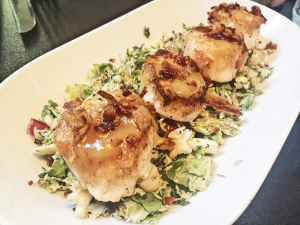 Seared scallops atop the apple brussels slaw. Bits of crumbled bacon rested on each scallop.