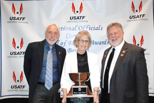 Kathy McLymond was named the Outstanding Field Official by USA Track & Field at the Association’s annual meeting earlier this year. With her are, at left, Vin Lannana, who was then president of USATF, and Mike Armstrong, USATF National Officials chairman. McLymond said the award bowl will hold enough popcorn for a movie. 