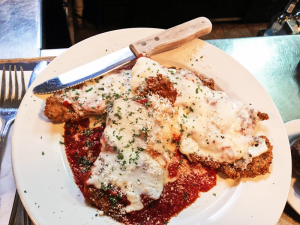 The veal parmesan entree features three loins covered in marinara sauce and melted mozzarella.