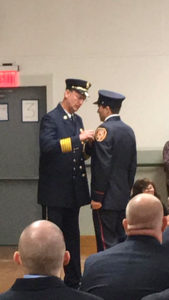 John Welker pins a badge on his son D.J. at the New York State Fire Academy graduation.