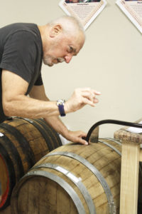 Tom Raco of Webster examining a new batch of wine produced by Wineworx. Raco and his friend Tony Toscano of Rochester created Wineworx in 2013.