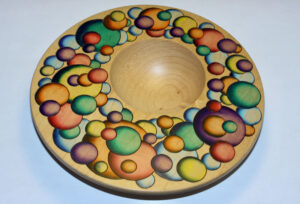 “The Universe of Color” — Each painted circle has a burned “border” around it. Made of maple, acrylic airbrush paint, pyrography. Inspired by a painting by Rochester artist Fritz Trautmann.
