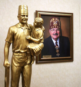 Inside the Damascus Shrine stands this statue of a Shriner carrying a little girl, and a picture of past Imperial Potentate Jim Smith. 