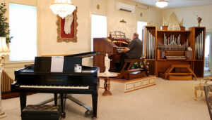The living room in Tim Schramm’s house features a grand piano, left, a theater organ, center, and a church organ. He has hosted hymn-sings there, and wants to make it a venue for local musical talent.